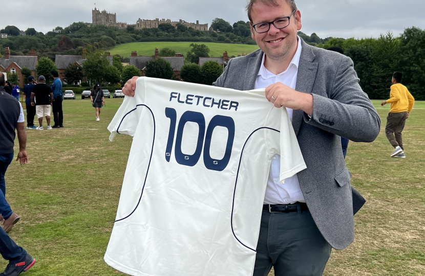 Mark holding a Cricket Shirt with 100 on it